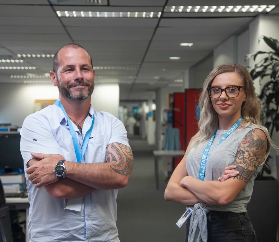 Two 2degrees employees wearing blue staff lanyards in an office